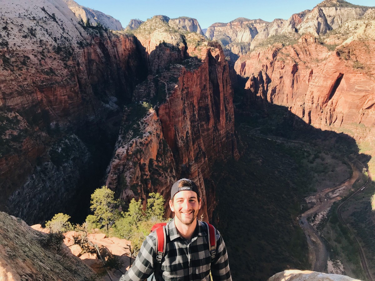 looking down at a man in the foreground and a large canyon below and behind him