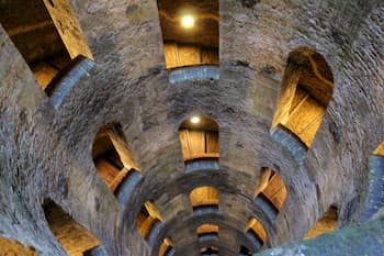 looking down a large well with windows revealing a surrounding staircase.