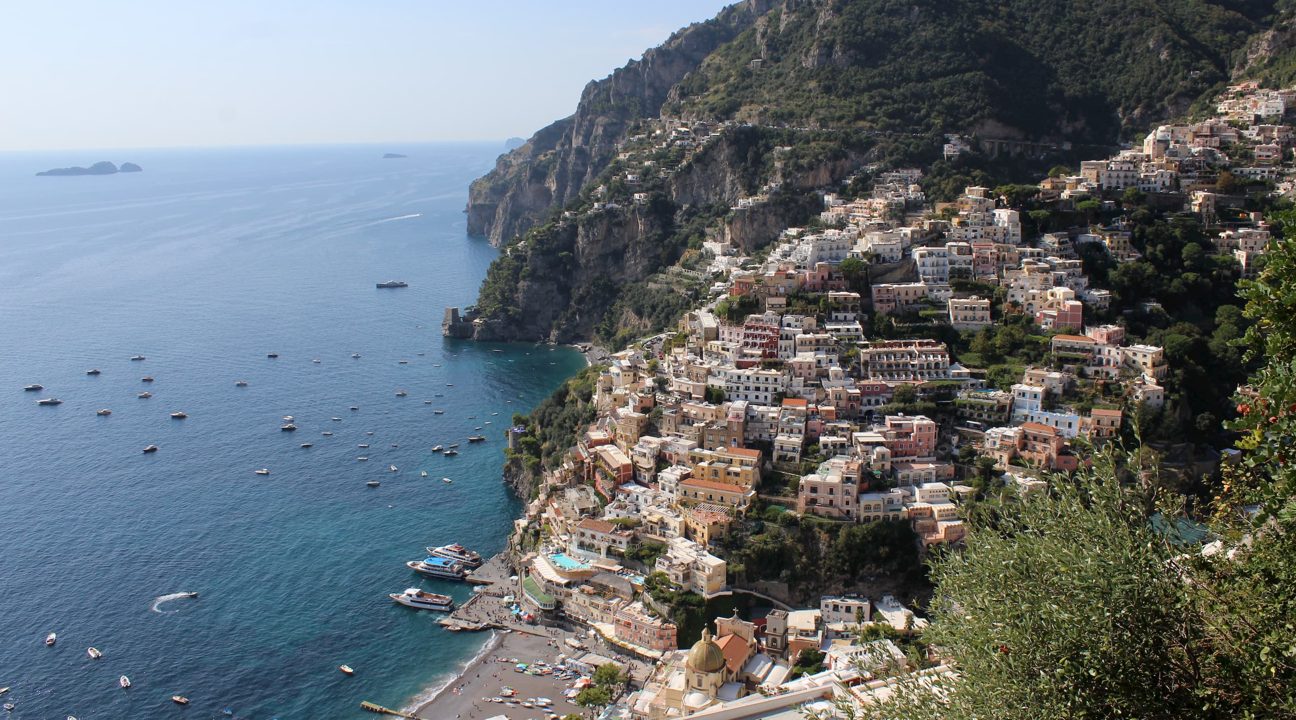 Town with builds built into coastal hillside and small boats in the water