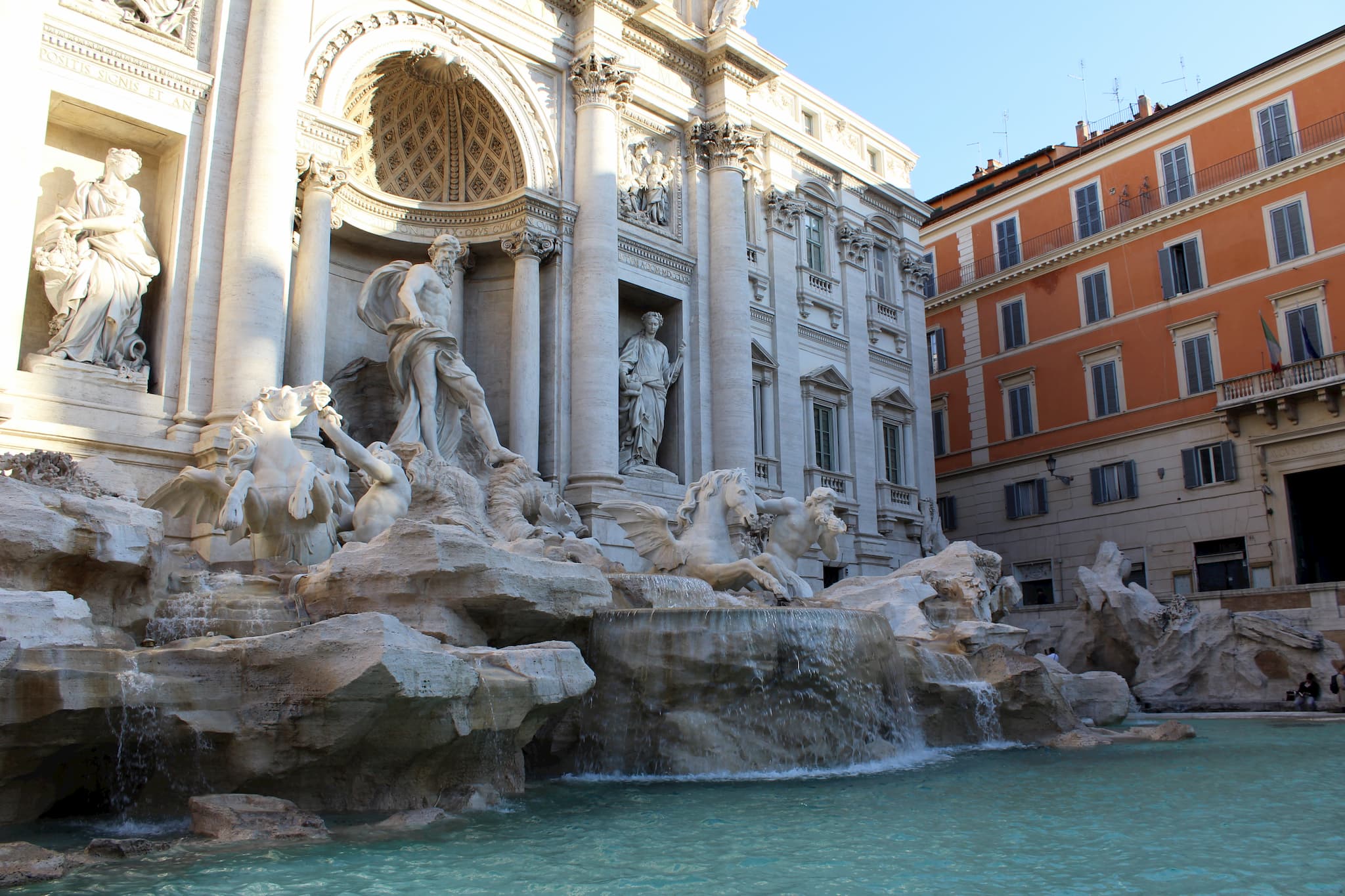 Marble carved statues forming a fountain behind a pool of water