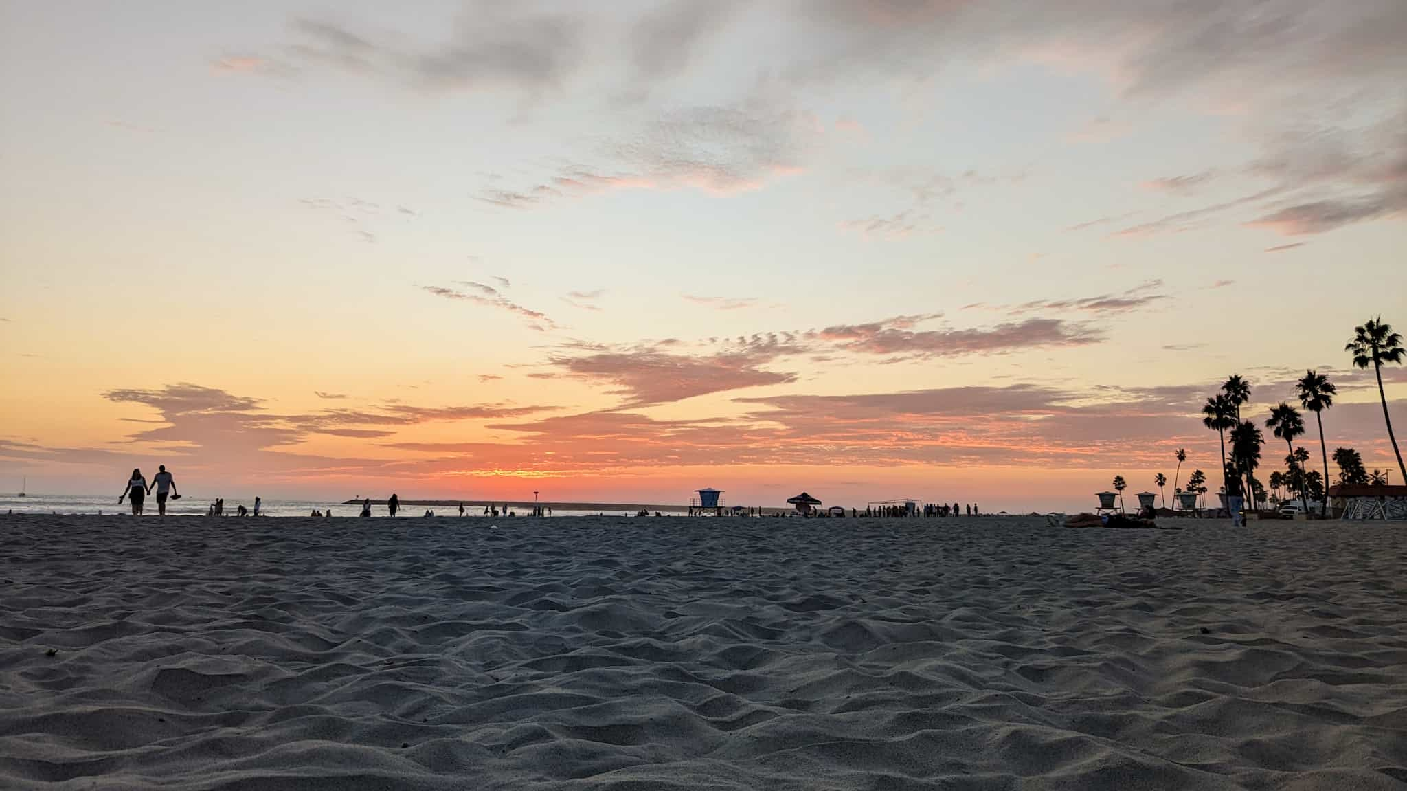 Sunset on a wide open beach with palm trees.