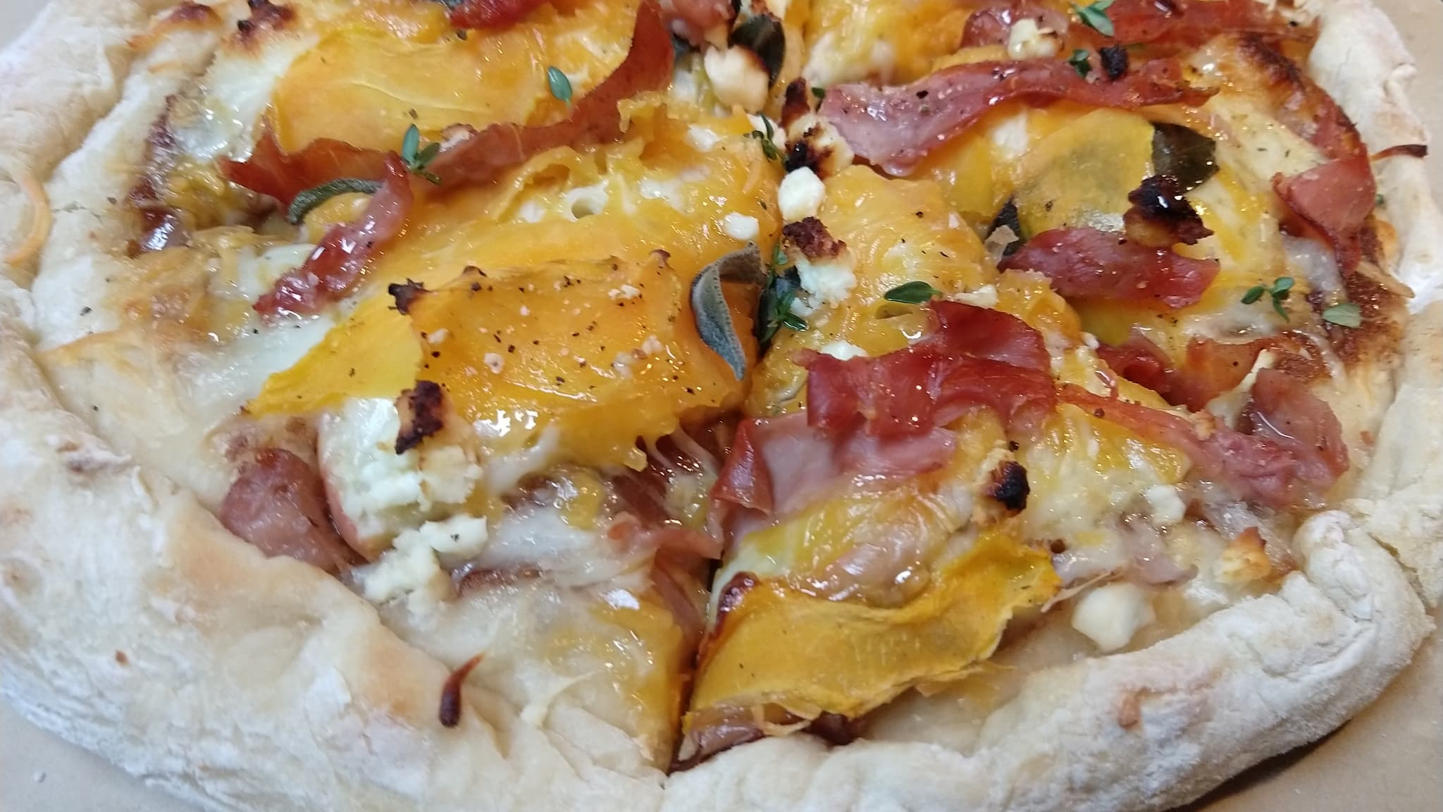 Pizza topped with prosciutto and butternut squash shavings