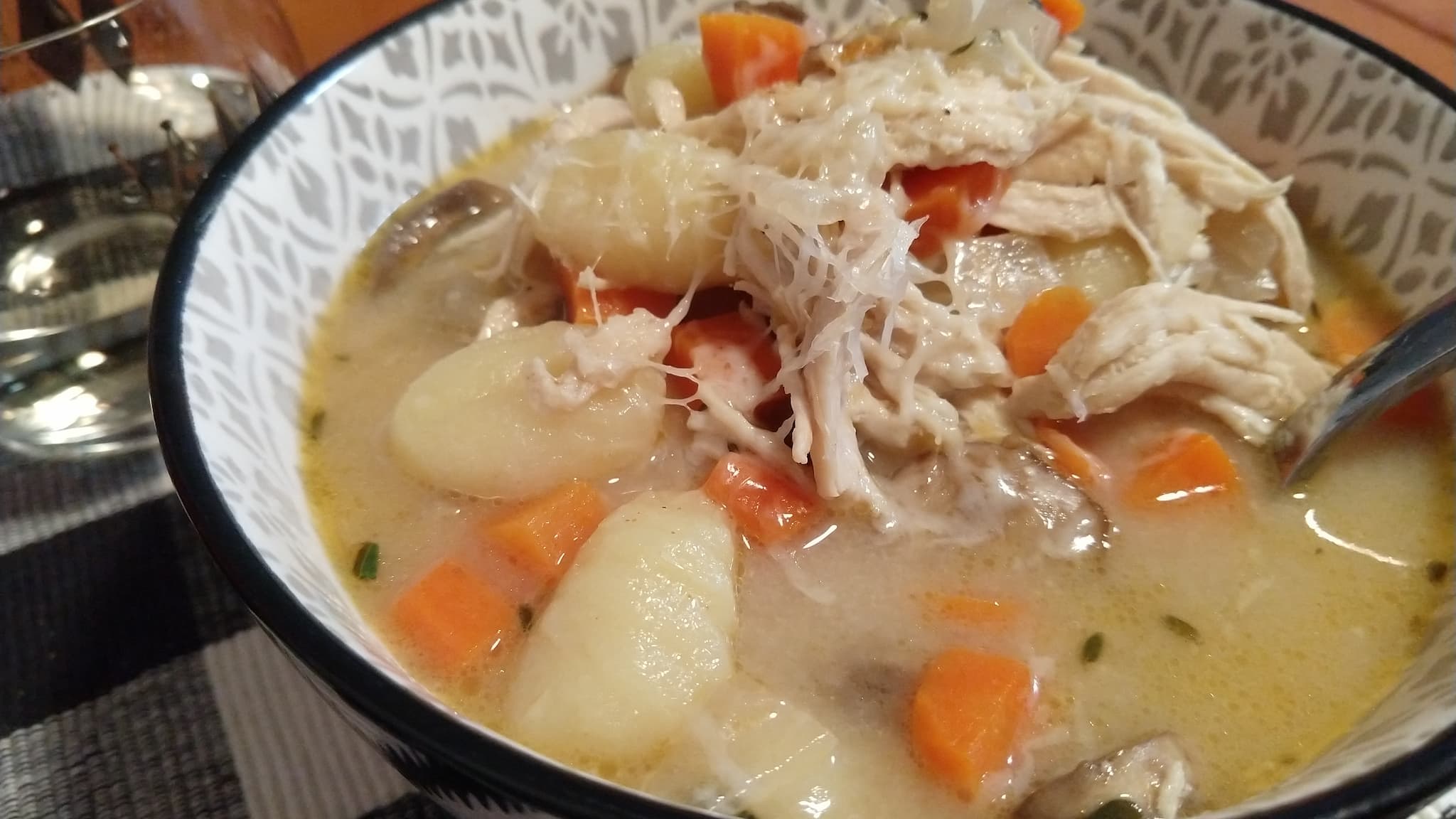 bowl of soup with carrots, shredded chicken, and gnocchi