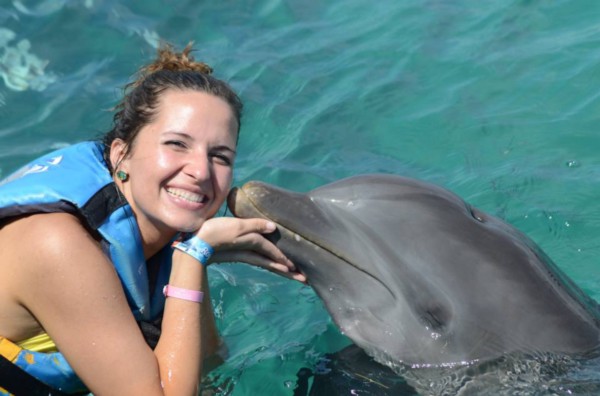 woman in life vest being kissed by a dolphin