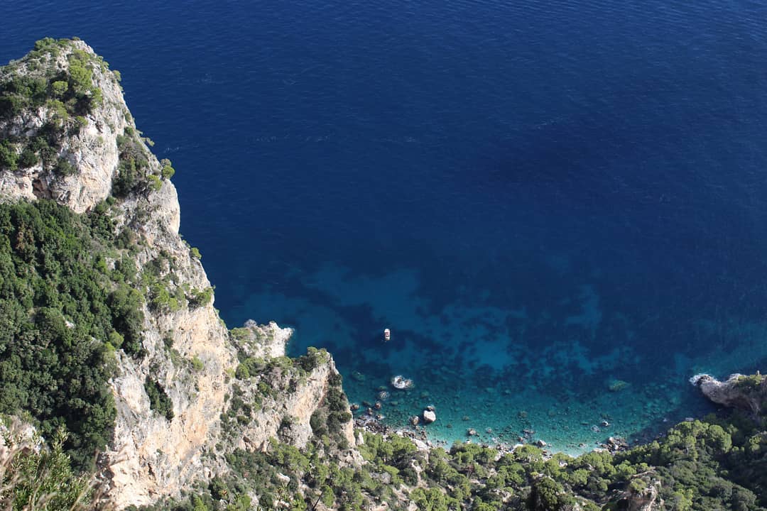 Looking down from cliff at blue body of water.