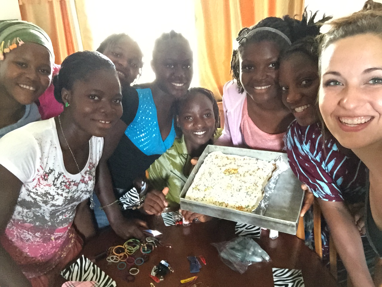 9 girls with a bake pan of cake with white icing