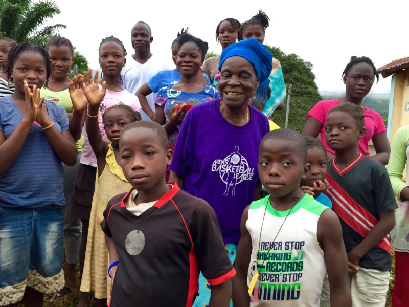 about 16 africans of varrious ages, some waving goodbye