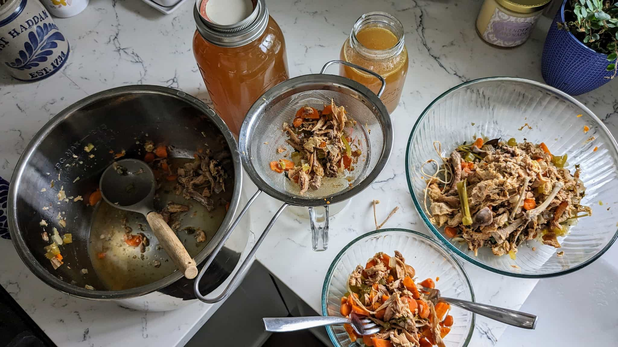 A collection of bowls, pots, and jars separating chicken broth, bones, meat, and vegetables.