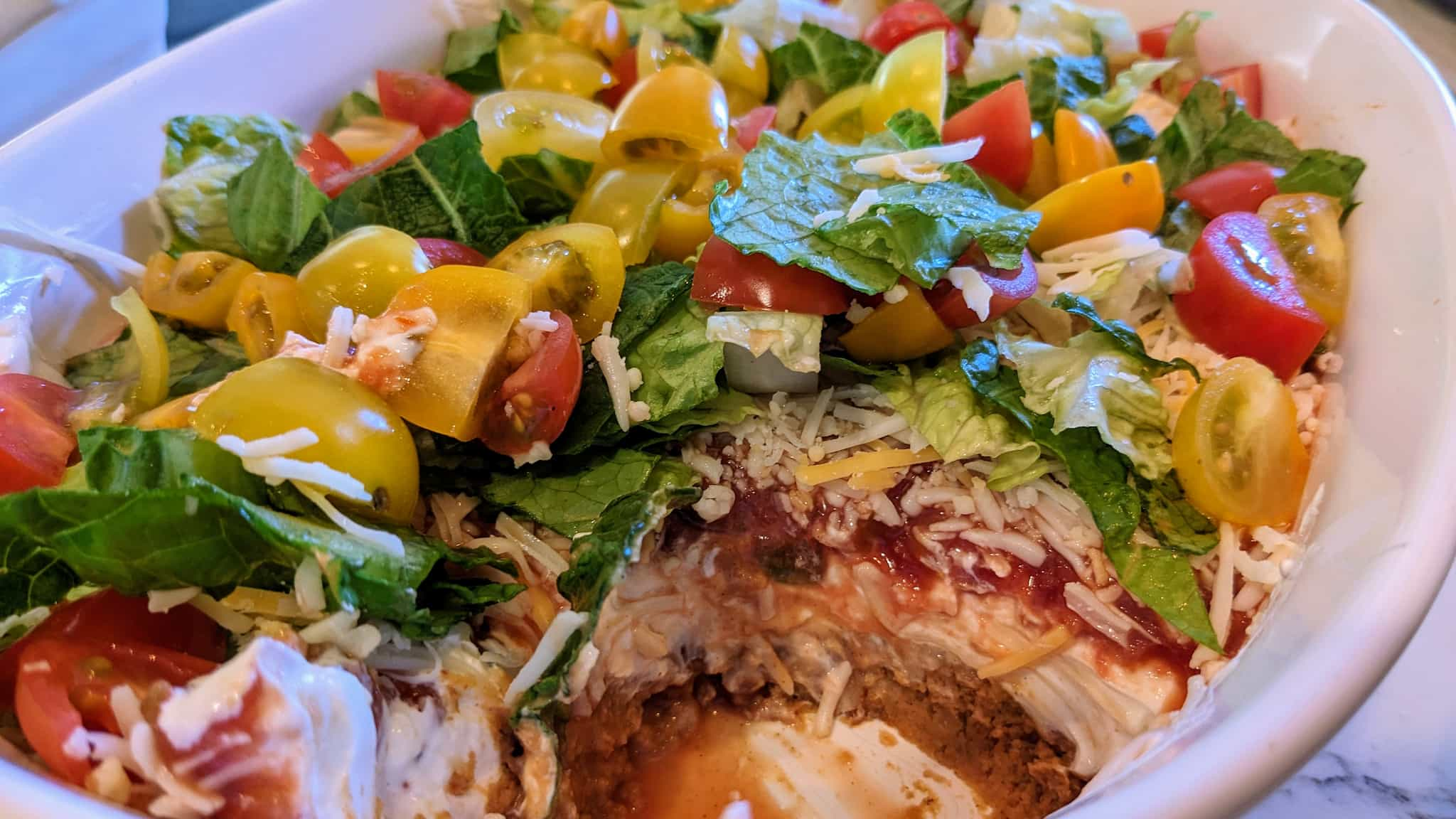 Casserole dish with dip topped with lettuce and tomatoes.