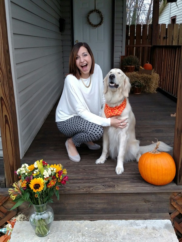 Woman and golden retriever on a house portch with autmn decorations all around