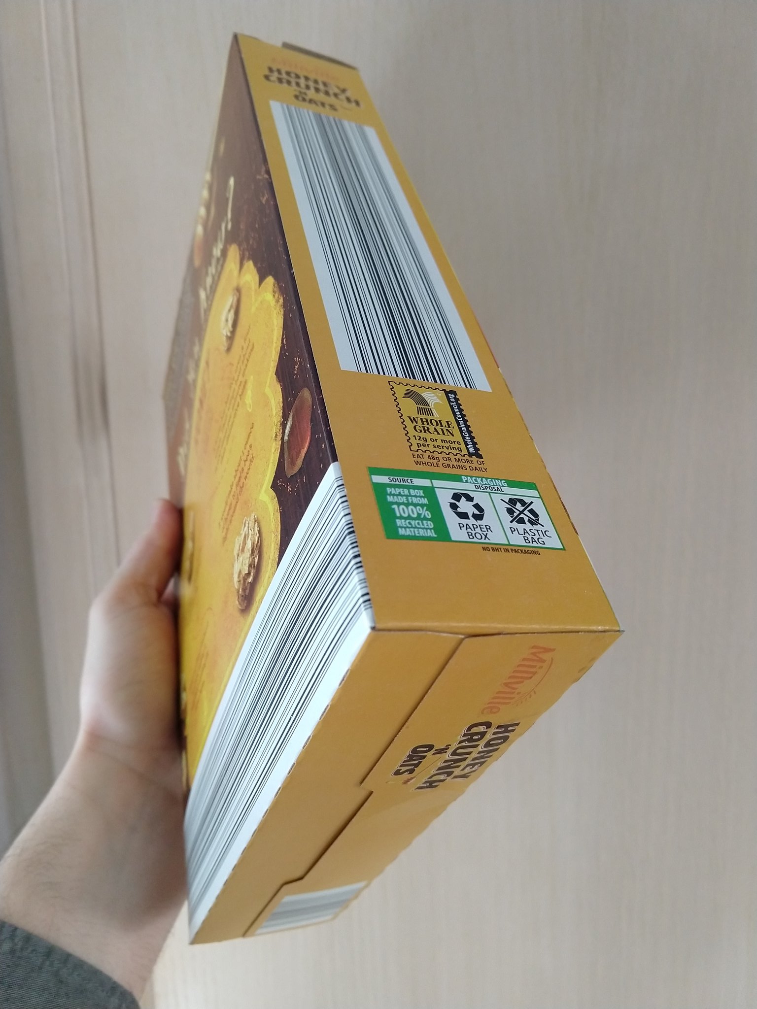 Person holding a cereal box with large sections covered in an elongated barcode.